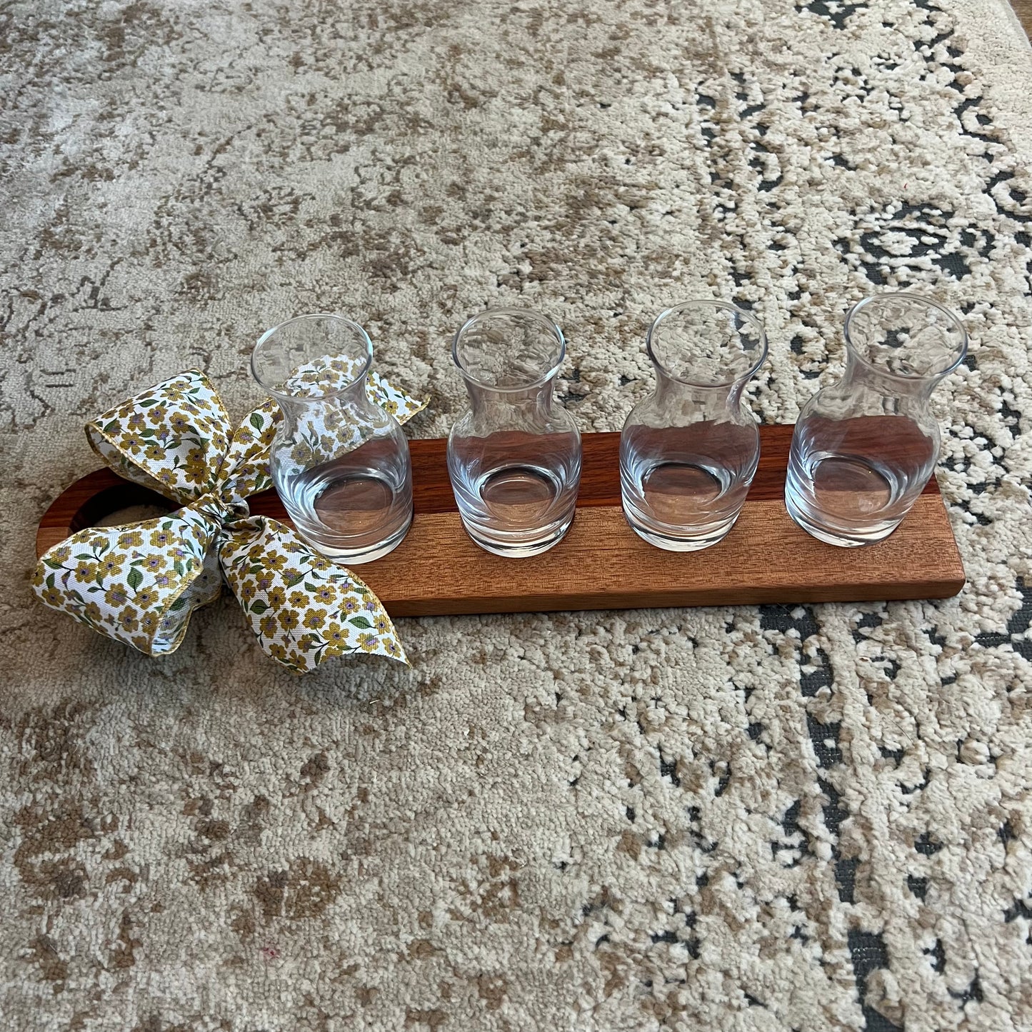 Handcrafted padauk and okoume wood wine flight with four glass carafes and a decorative bow on the handle