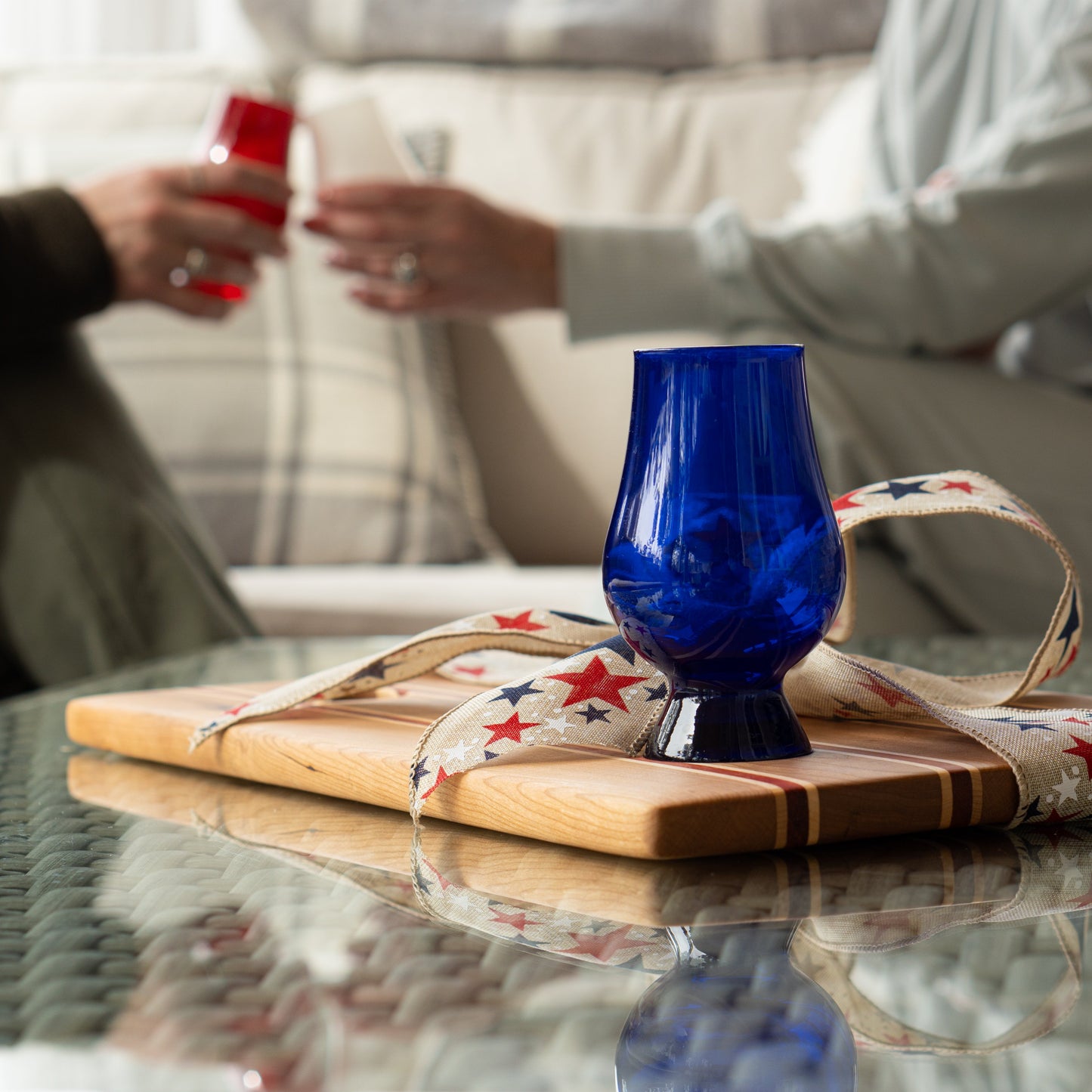 Blue Glencairn glass on a patriotic wooden bourbon flight board with people in the background