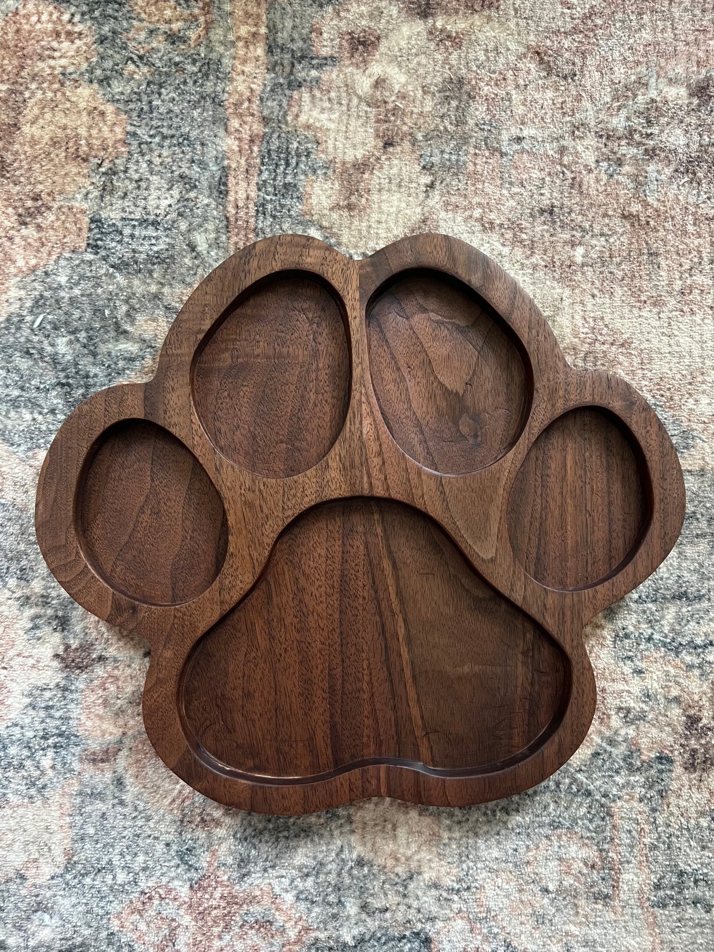 Handcrafted walnut wood snack tray in the shape of a paw print with five carved compartments.