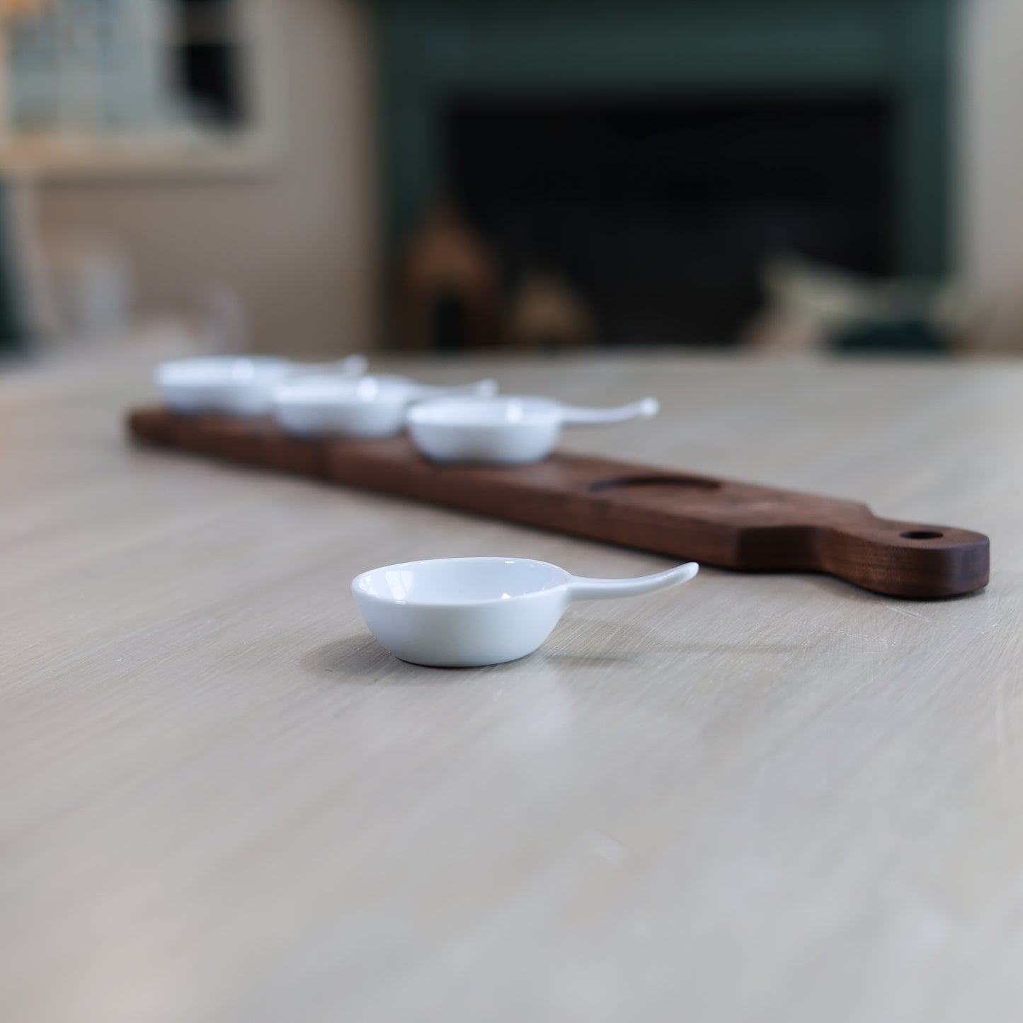 Side view of walnut serving board with white mini bowls for dips and tastings
