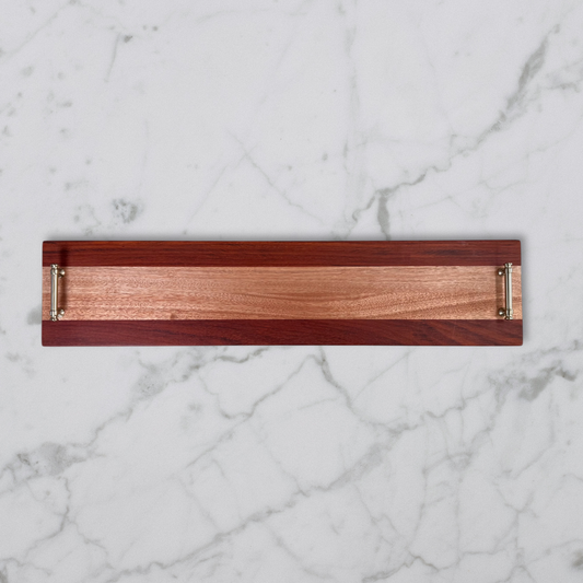 Wooden charcuterie tray with brass handles on a marble background