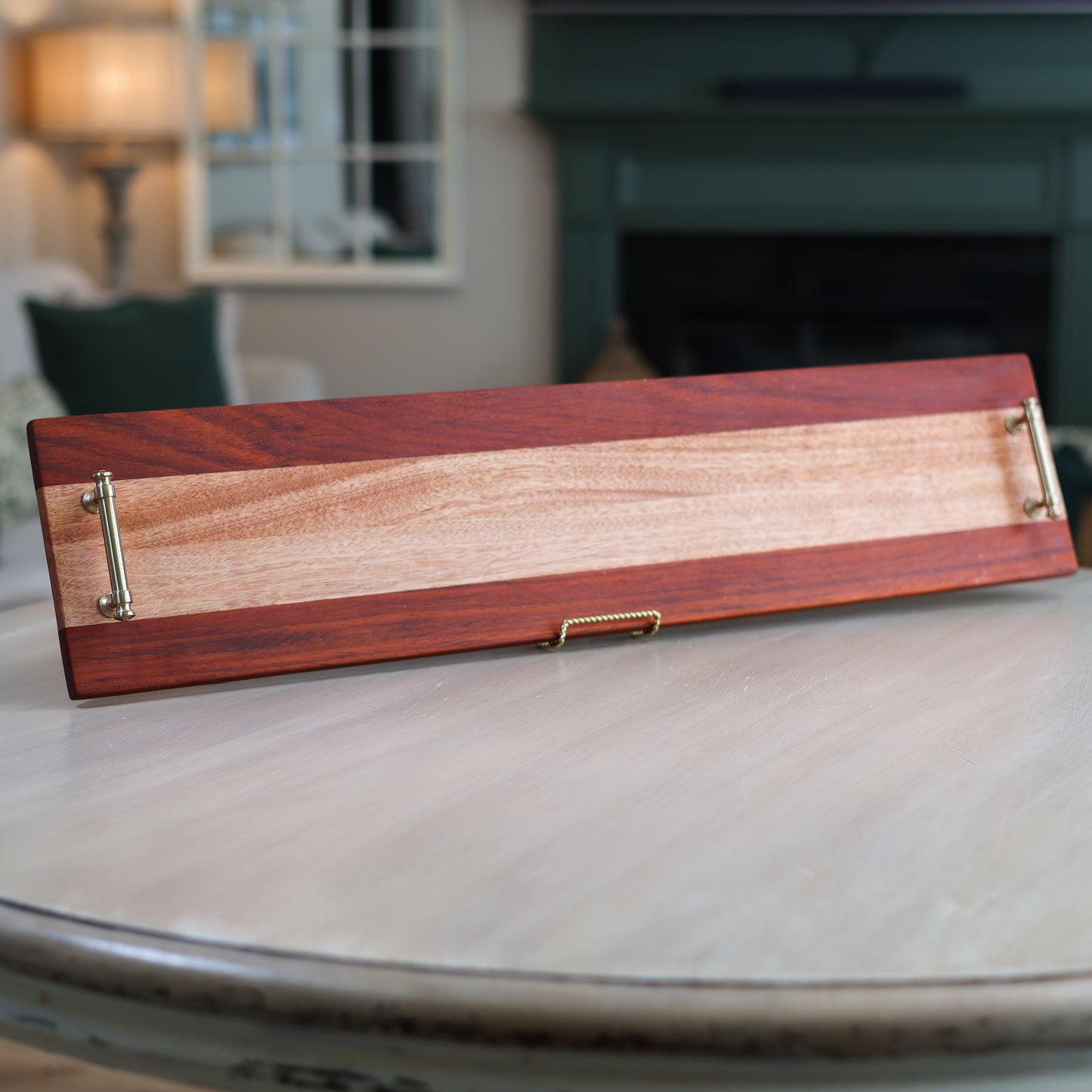 Wooden charcuterie tray with brass handles on a table in a living room setting