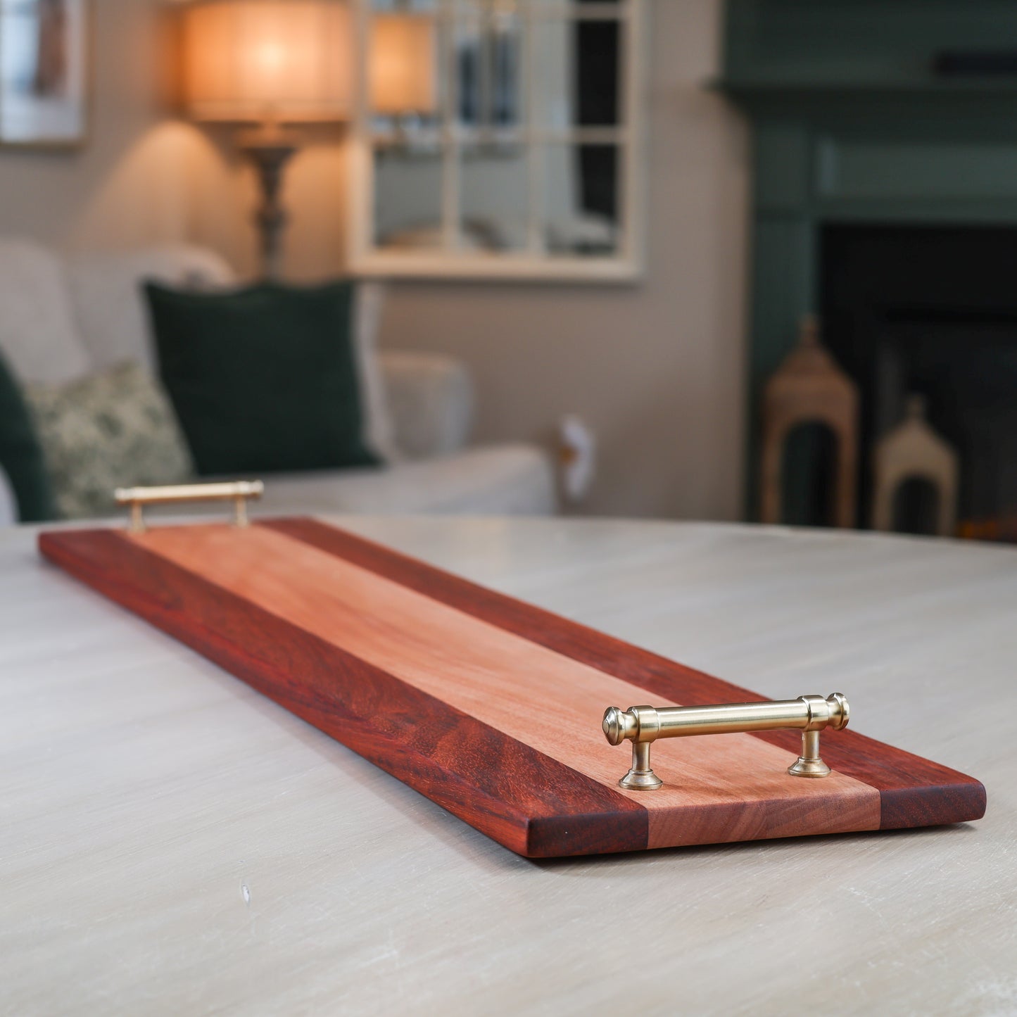 Wooden charcuterie tray with brass handles on a table in a living room setting