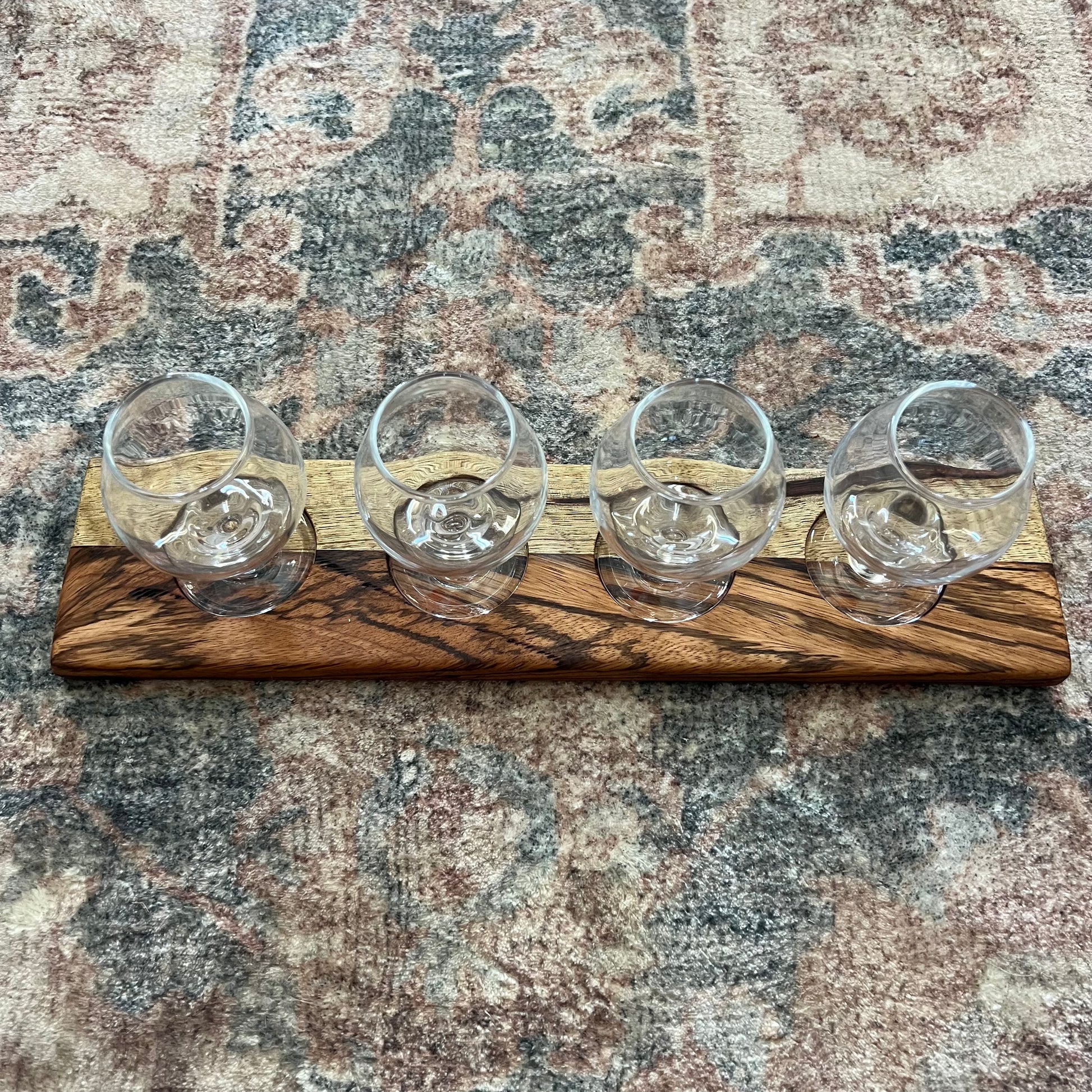 Handcrafted bourbon and whiskey flight board made from Black Limba and Zebrawood with four glass carafes