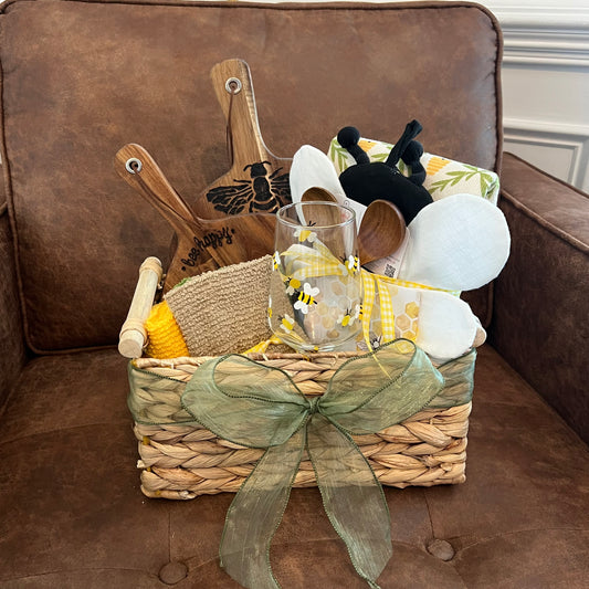 Bee-themed gift basket with round hand-burned acacia boards, hand-painted wine glass with stem, dish towels, oven mitt, pot holder, and kitchen cloths.
