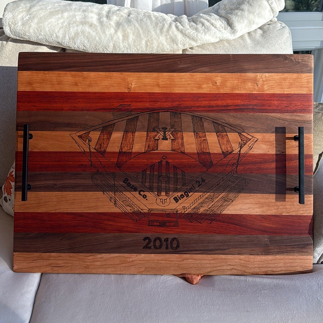 Wooden cutting board with a ship design and '2010' engraving on a white couch.