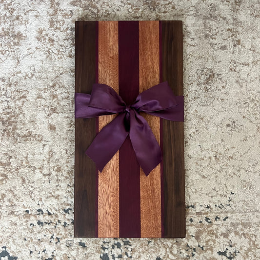 Charcuterie board made from walnut, purpleheart, and okoume wood, measuring 20¾ by 10.5 inches with rich contrasting tones and smooth finish.