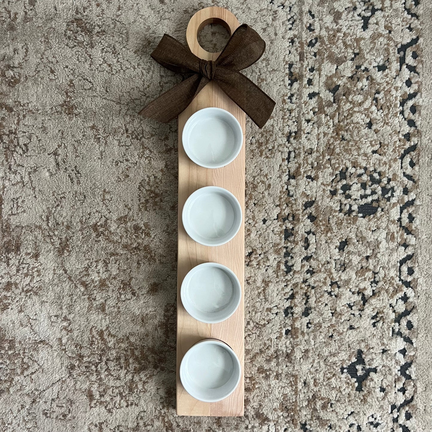 Handcrafted cherry and maple wood flight with a rounded handle, bow accent, and four white dipping bowls. Approximately 24 inches long.