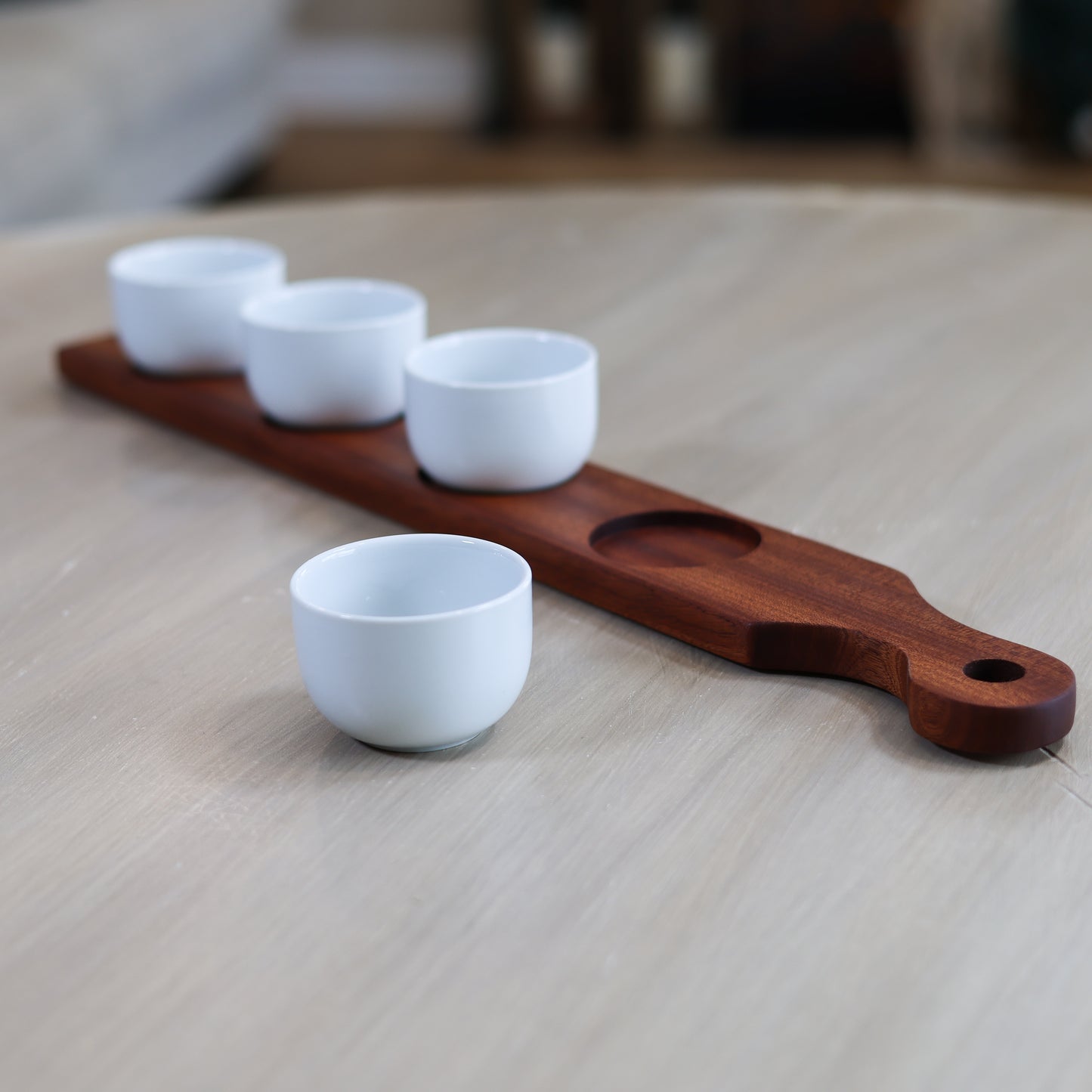 Side view of cherry and maple dip board with handle and white dipping bowls for serving