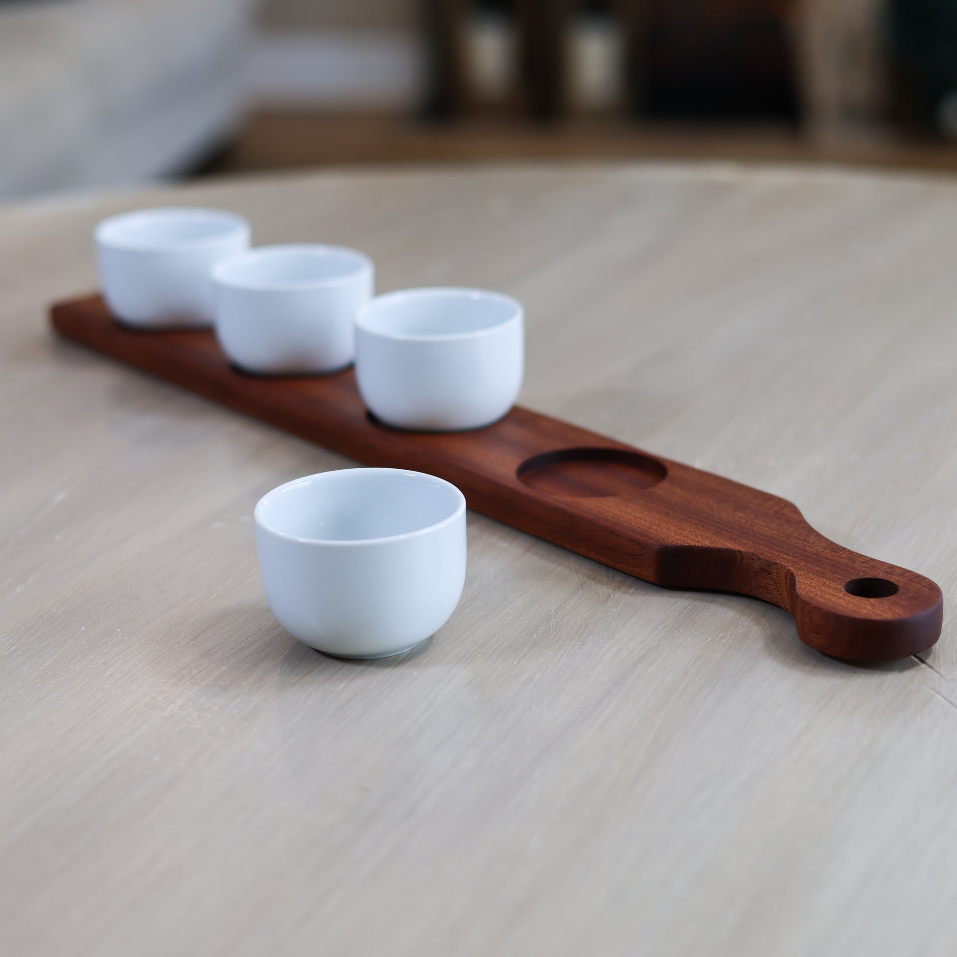Side view of cherry and maple dip board with handle and white dipping bowls for serving