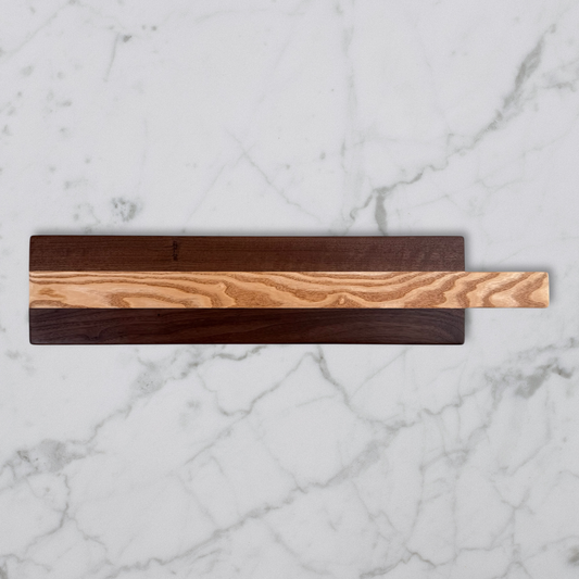Wooden charcuterie board with two distinct wood types on a marble surface