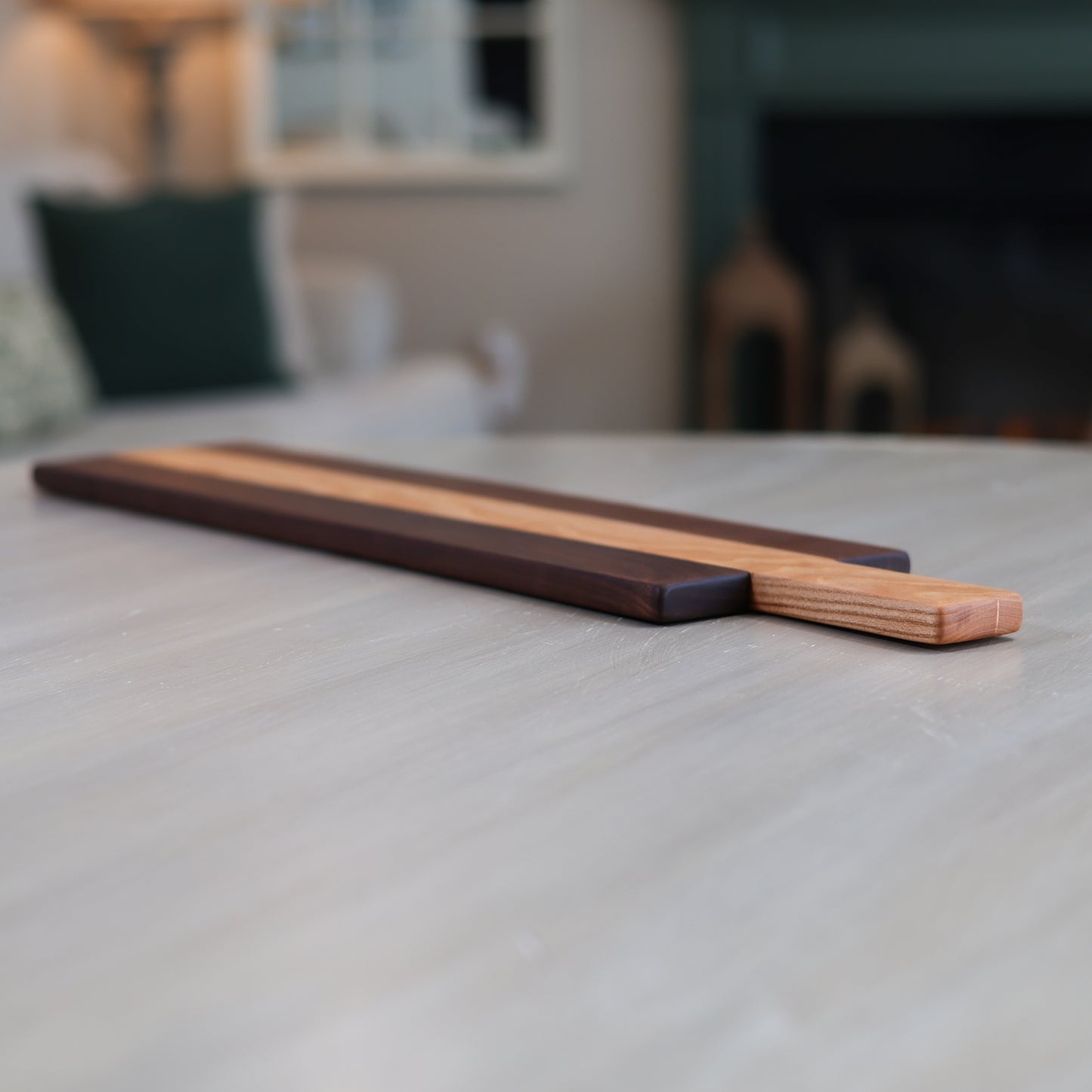 Wooden charcuterie board with two distinct wood types on a table in a living room
