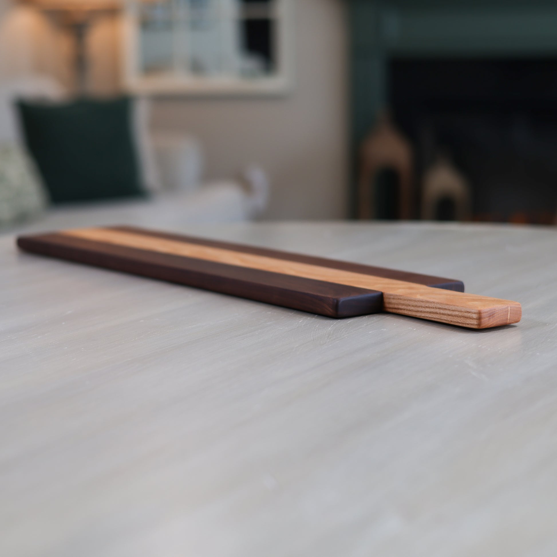 Wooden charcuterie board with two distinct wood types on a table in a living room