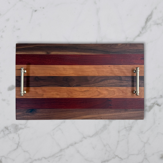 Wooden serving tray with striped pattern and metallic handles on a marble background