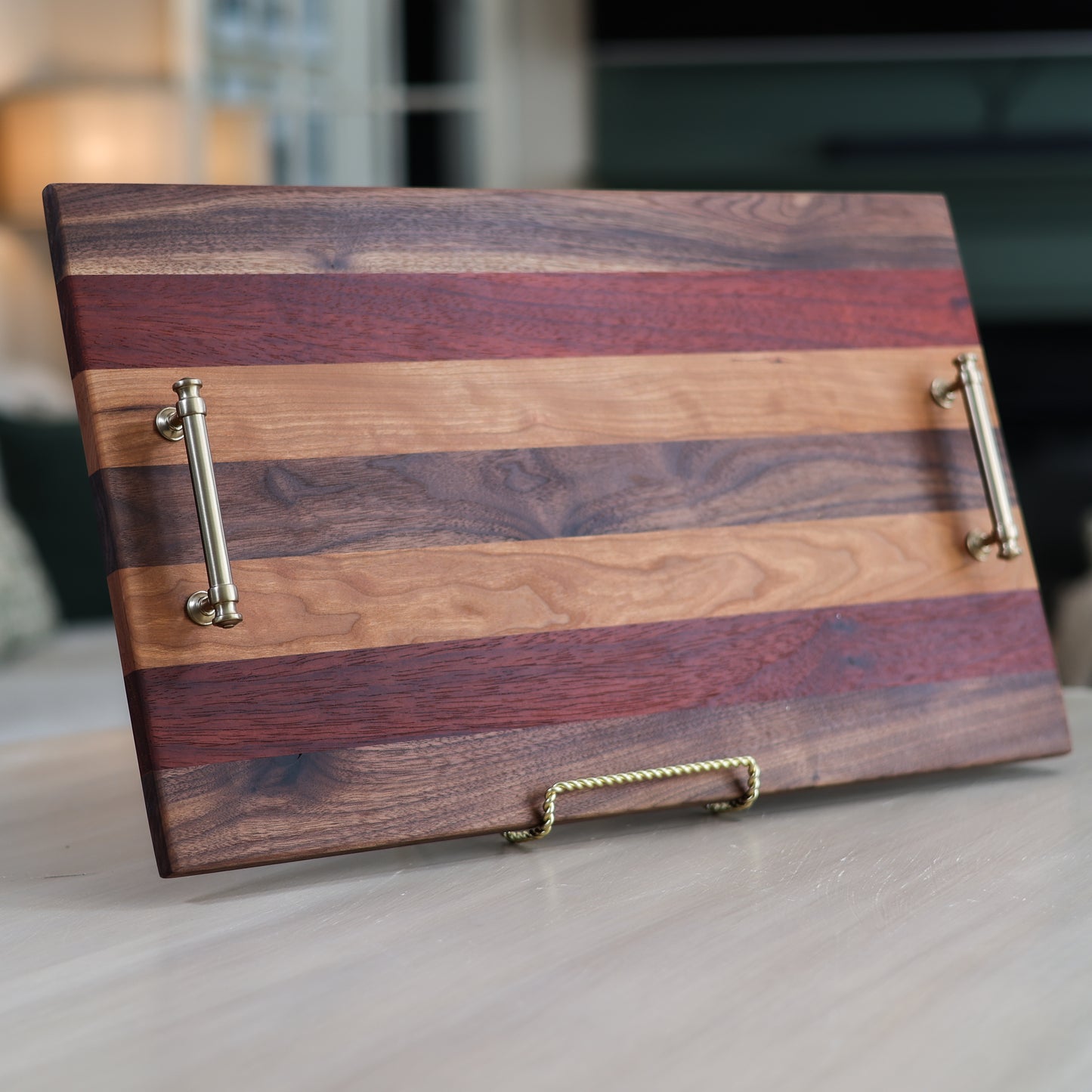 Wooden serving tray with striped pattern and metallic handles in a living room