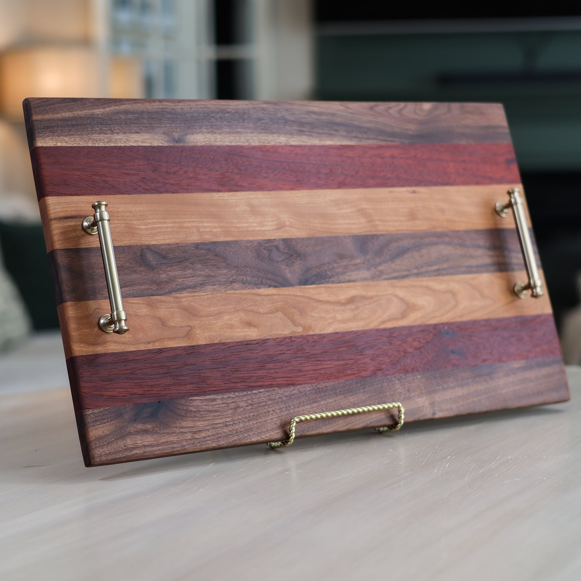 Wooden serving tray with striped pattern and metallic handles in a living room