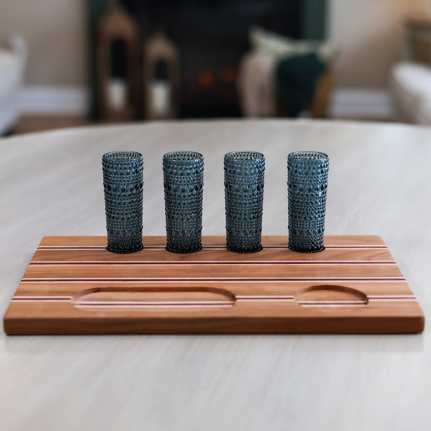 Cherry, maple, and padauk tequila flight with four shot glasses arranged on wooden board