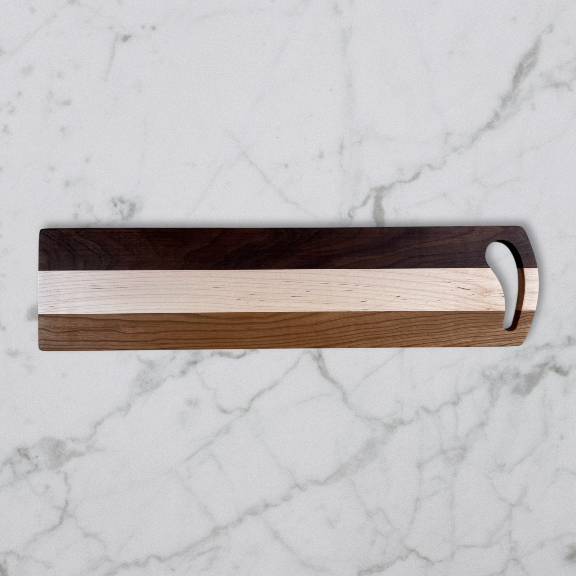 Wooden Charcuterie board with a handle on a marble surface