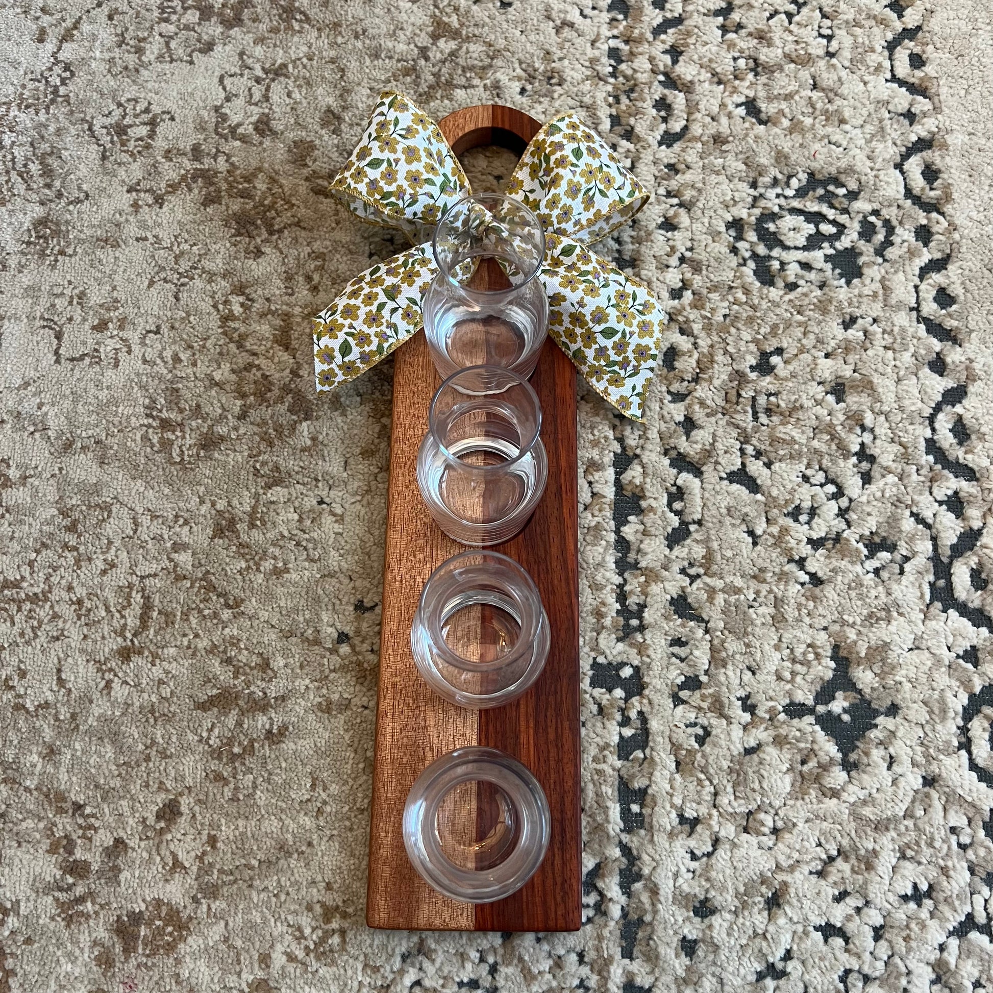 Handcrafted padauk and okoume wood wine flight with four glass carafes and a decorative bow on the handle