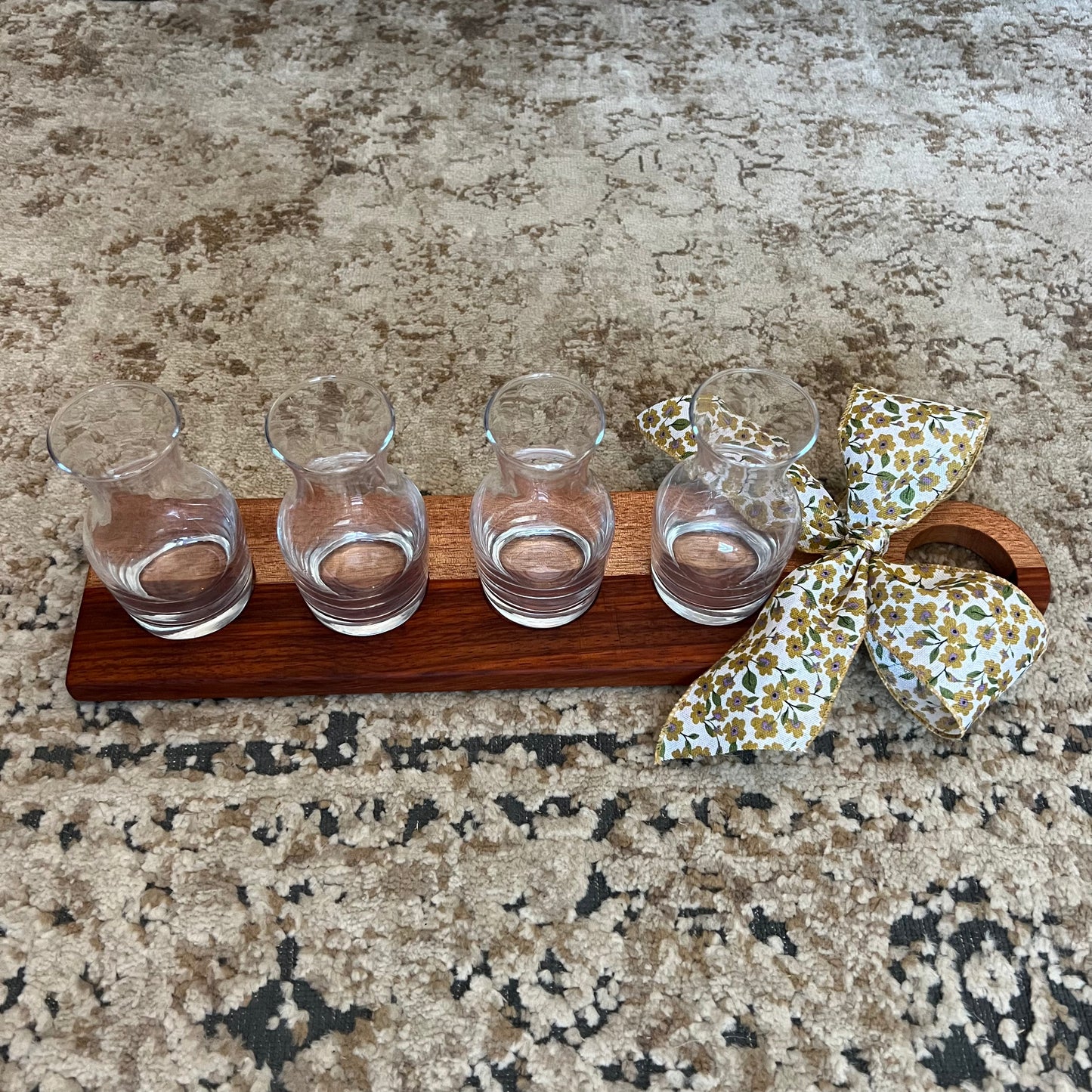 Handcrafted padauk and okoume wood wine flight with four glass carafes and a decorative bow on the handle