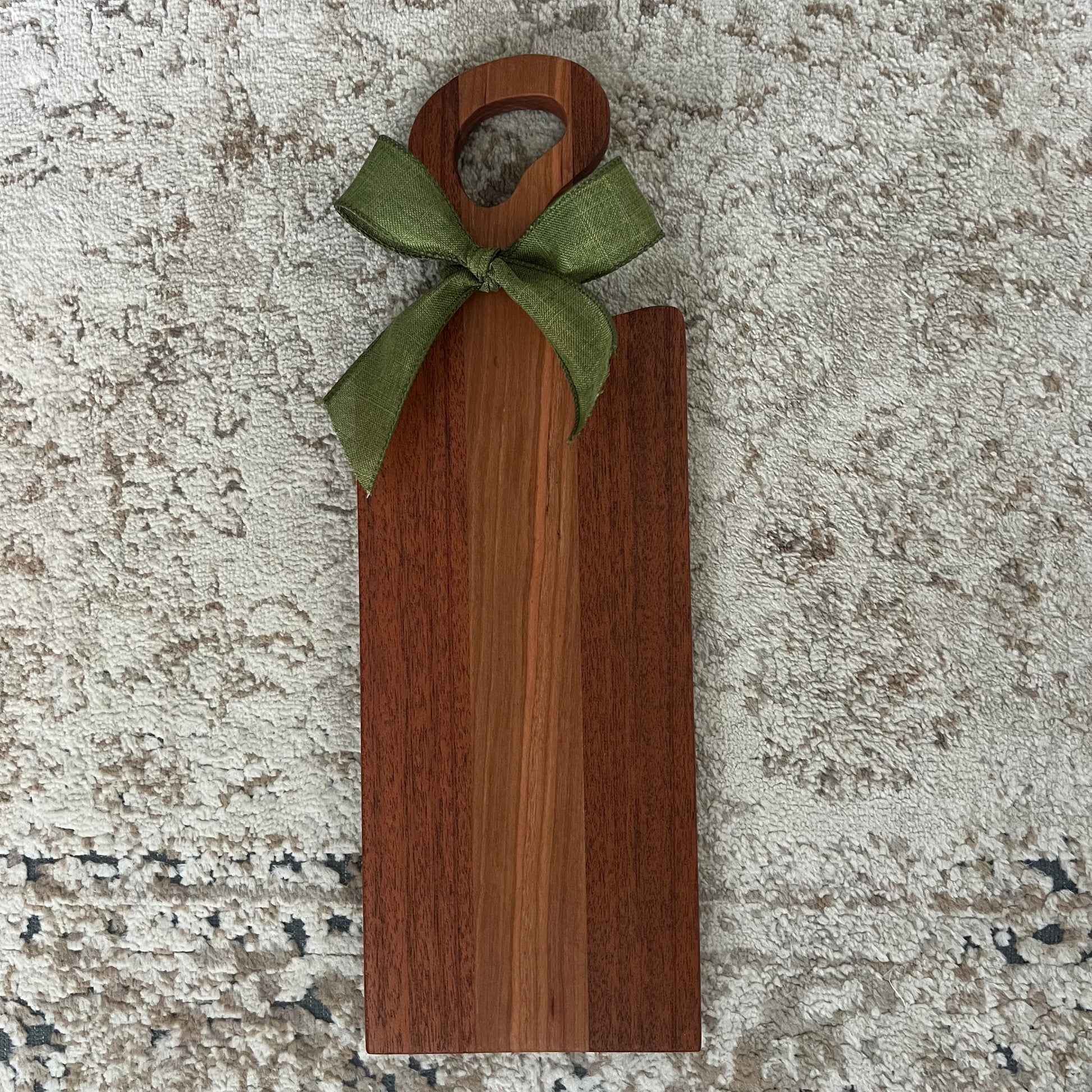 Handcrafted Merbau and Cherry wood bread board with single handle and green decorative bow, featuring rich contrasting tones and smooth finish.