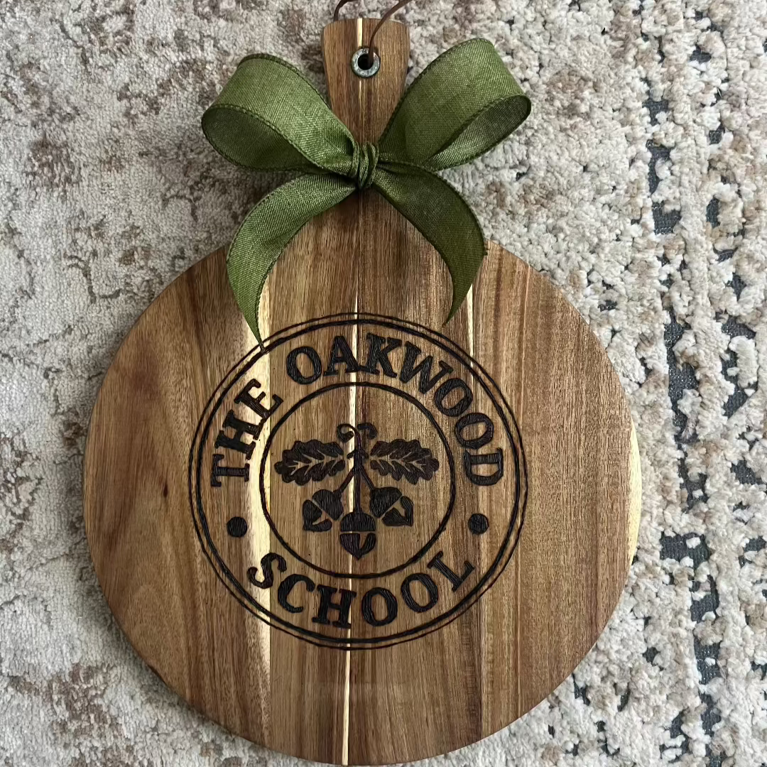 Hand-burned wooden board featuring The Oakwood School logo, with detailed lines and clean engraving on natural hardwood.