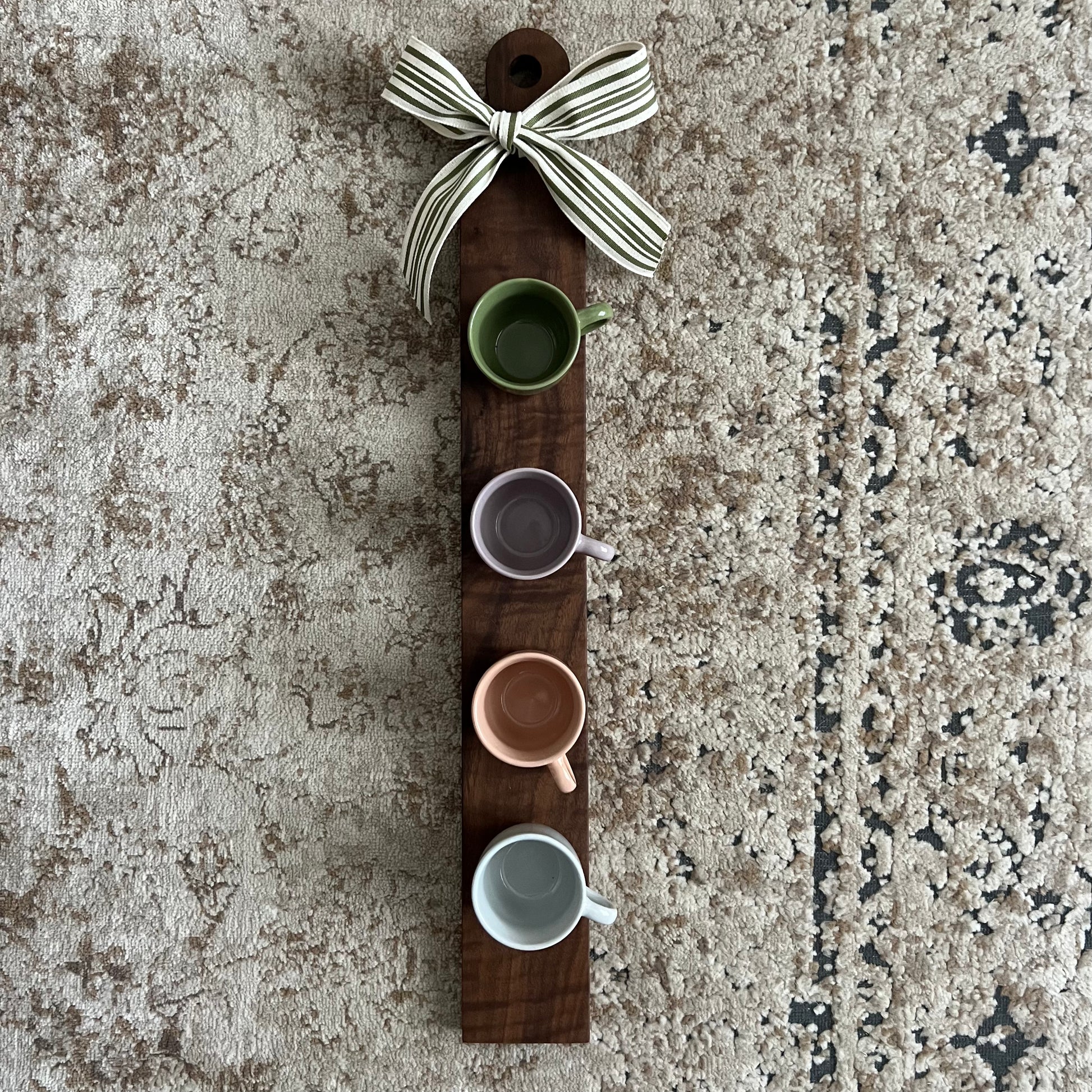Handcrafted walnut coffee flight board featuring four tasting cups evenly spaced on a long, narrow wooden board.