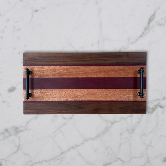 Wooden serving board with black handles on a marble surface