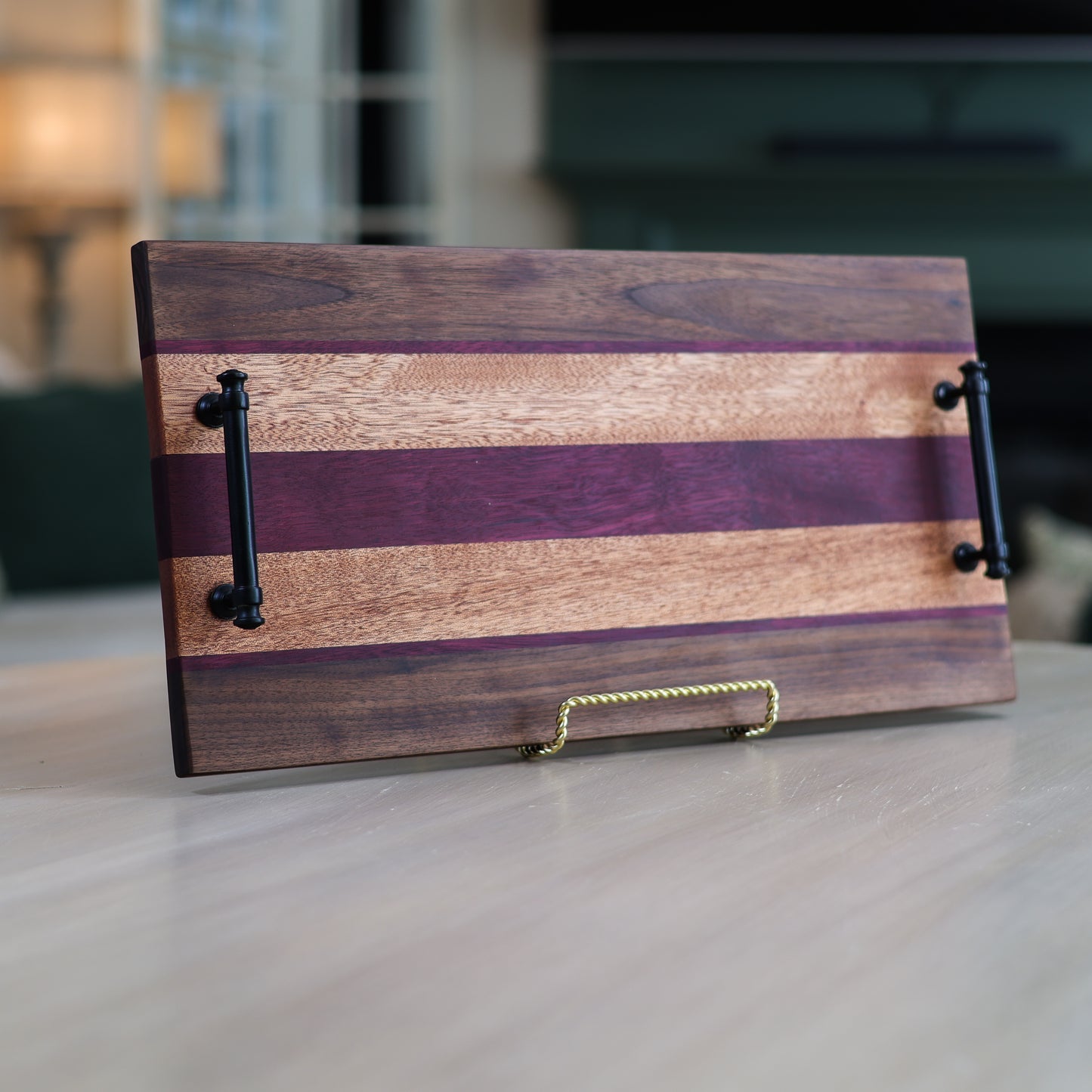 Wooden serving board with black handles in a living room setting