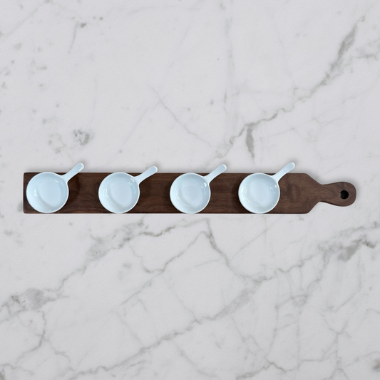 Walnut wood mini bowl flight board with four white ceramic bowls on marble surface