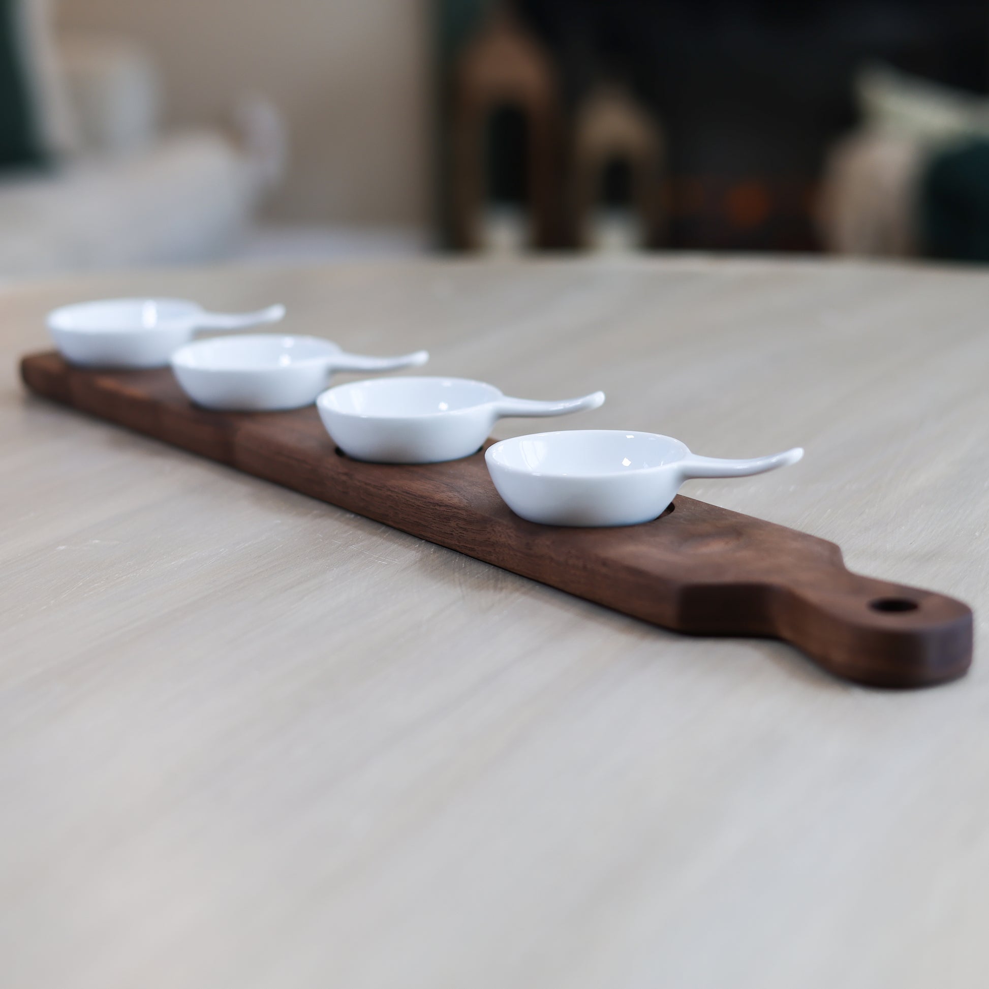 Walnut mini bowl flight with four white dipping bowls arranged on wooden serving board