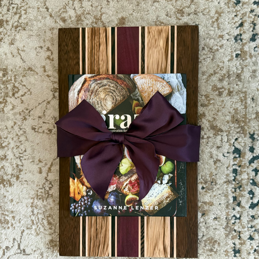 Wooden cutting board with a purple ribbon on a textured surface
